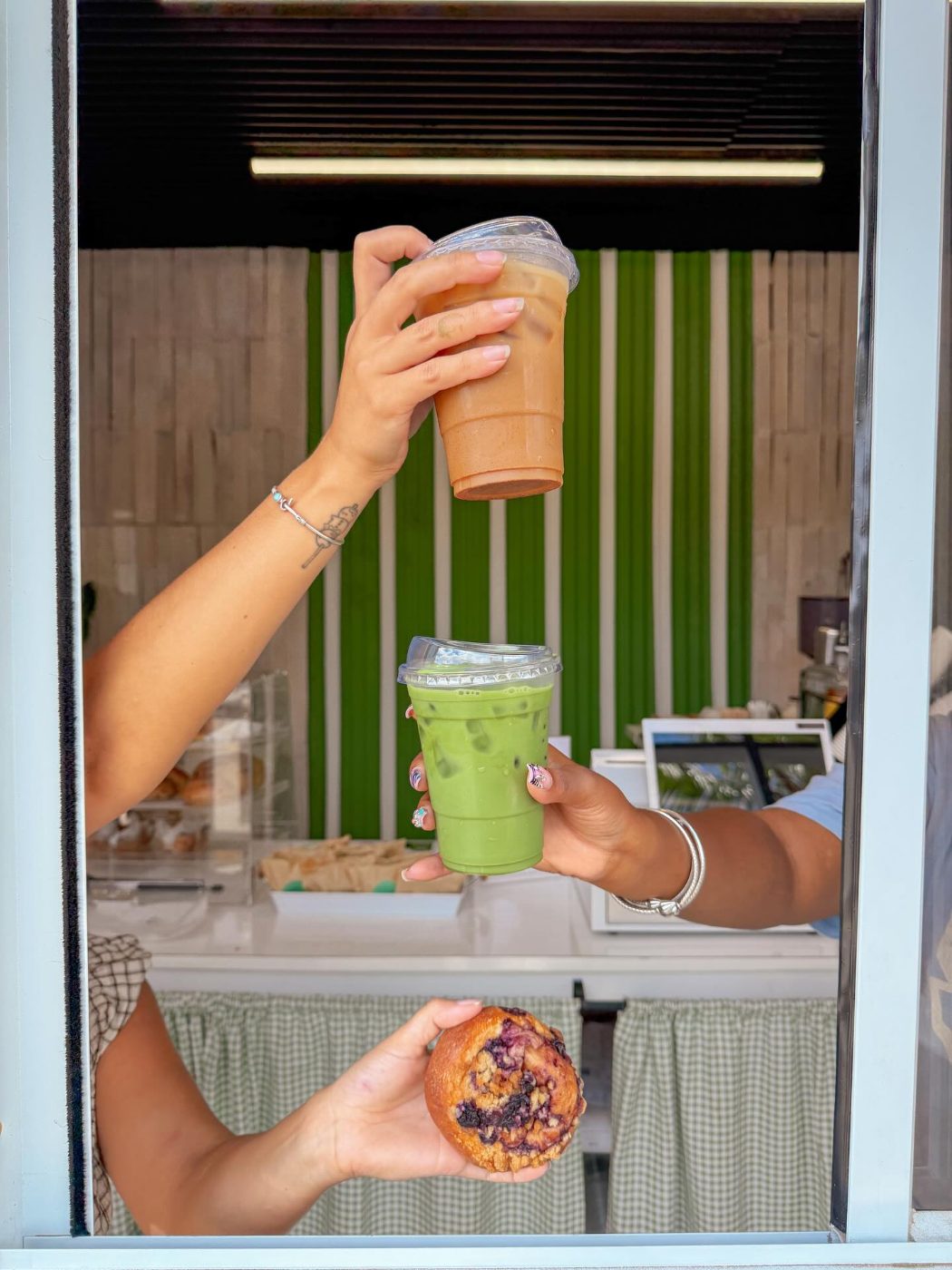 Two drinks and a blueberry muffin handed through the service window at The Roasted Coconut